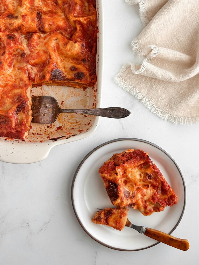 En gyllene vegetarisk lasagne i en vit ugnsform direkt ur ugnen